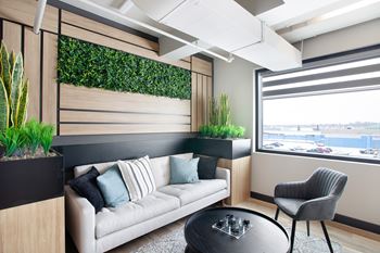 A living wall with plants on the side of a room with a couch and chair.